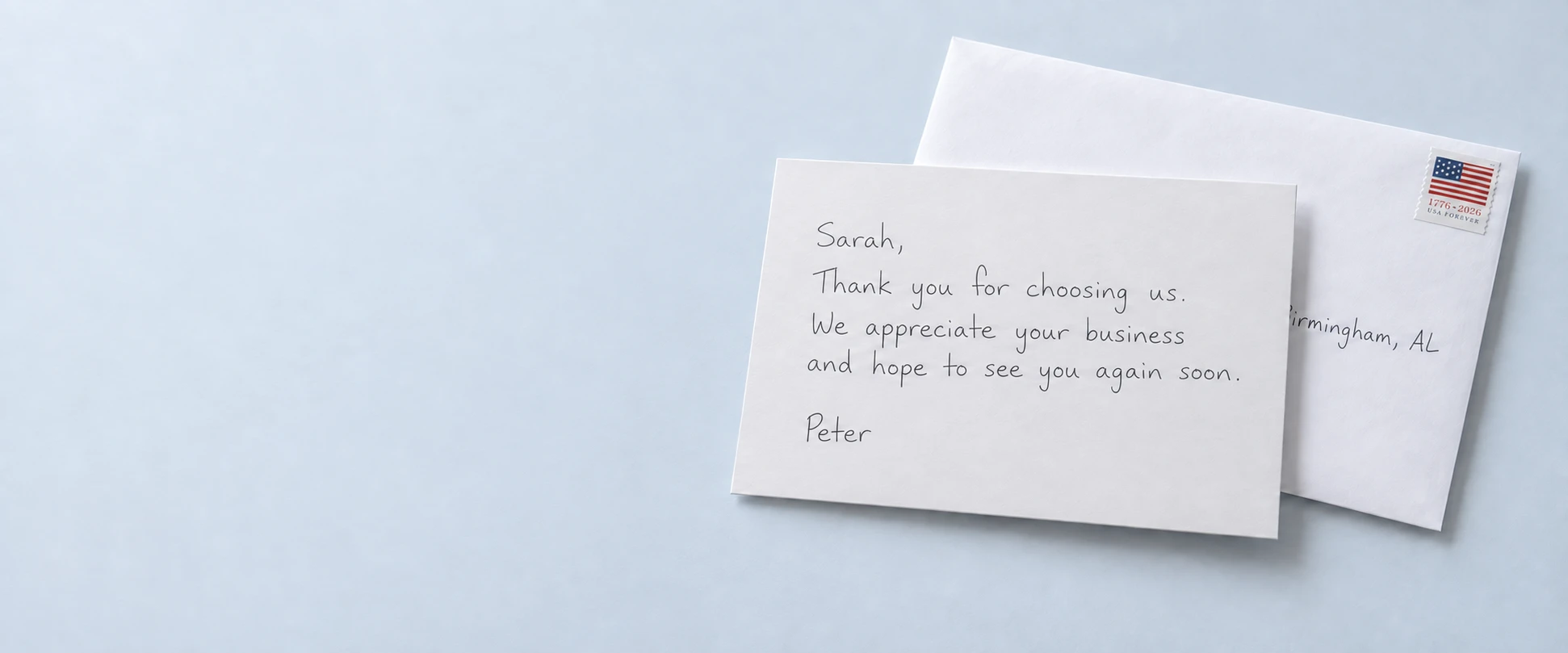 White handwritten thank-you card with a stamped white envelope